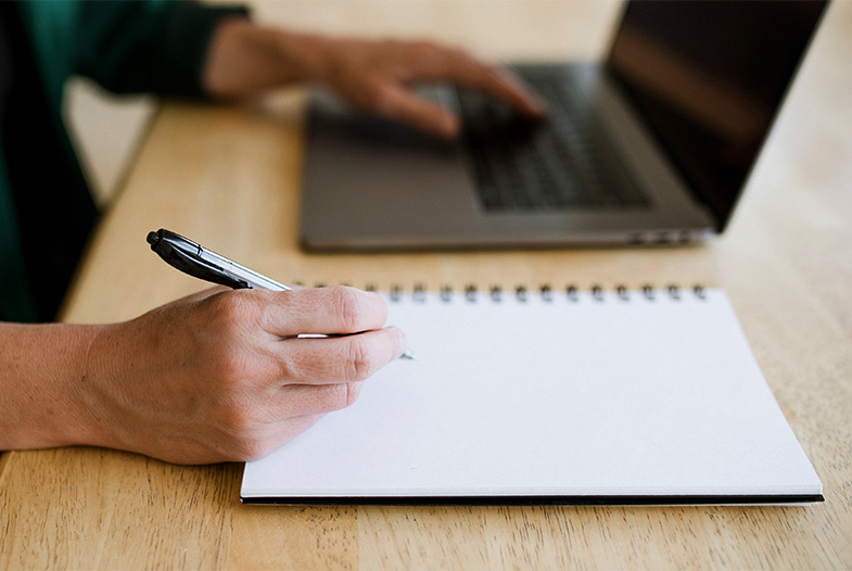 working on a laptop and taking notes